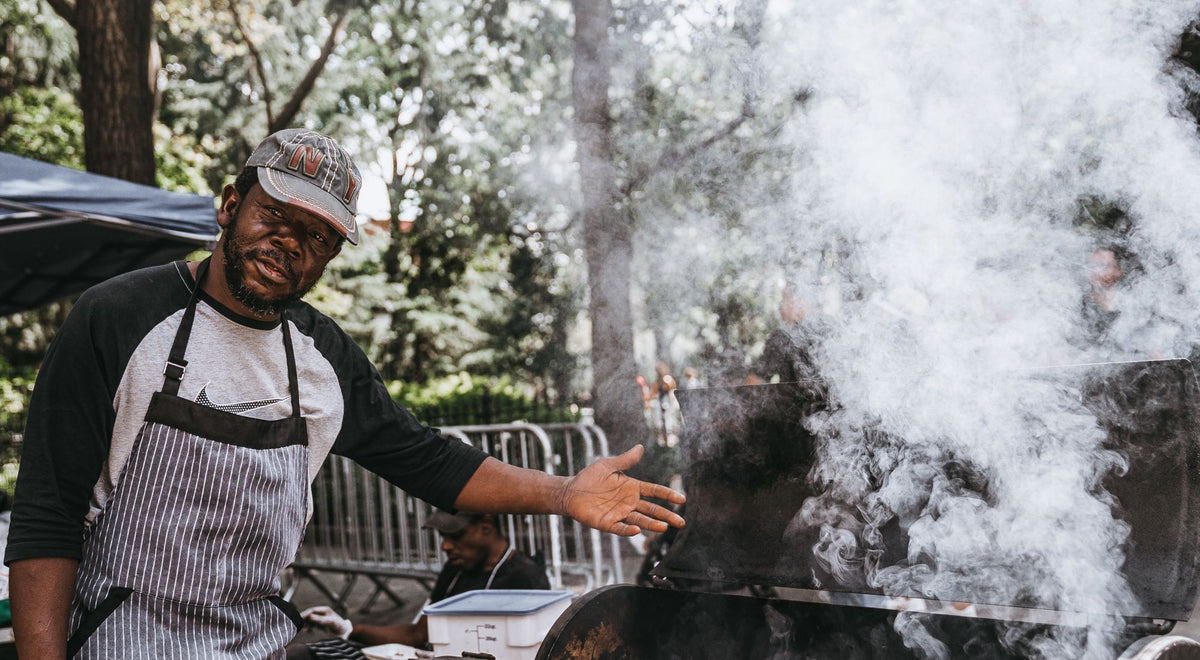 Homme portant un tablier de barbecue devant un grill en extérieur