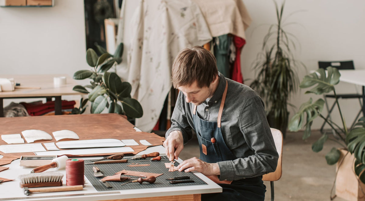 Artisan en tablier de protection travaillant à son établi dans un atelier
