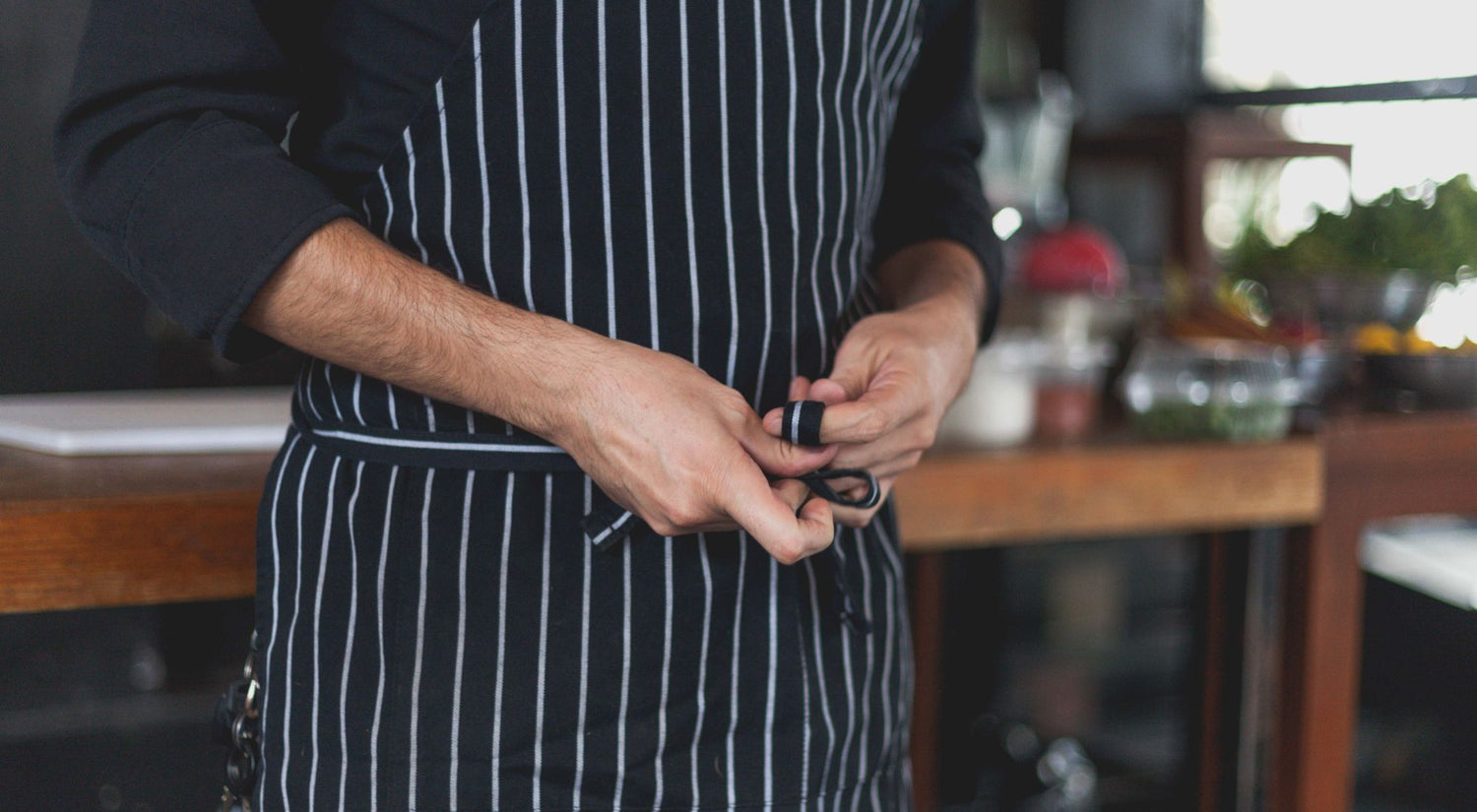 Cuisinier professionnel nouant son tablier dans une cuisine professionnelle