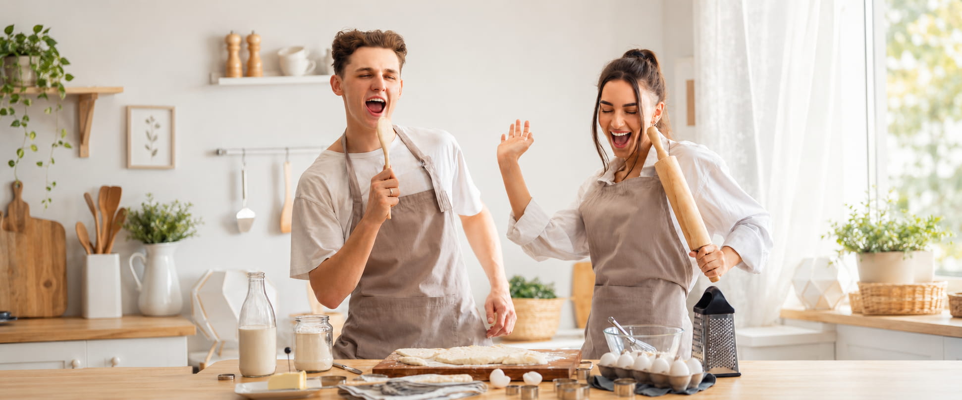 Couple s'amusant à cuisiner en tabliers de cuisine Petit-Tablier dans une cuisine lumineuse