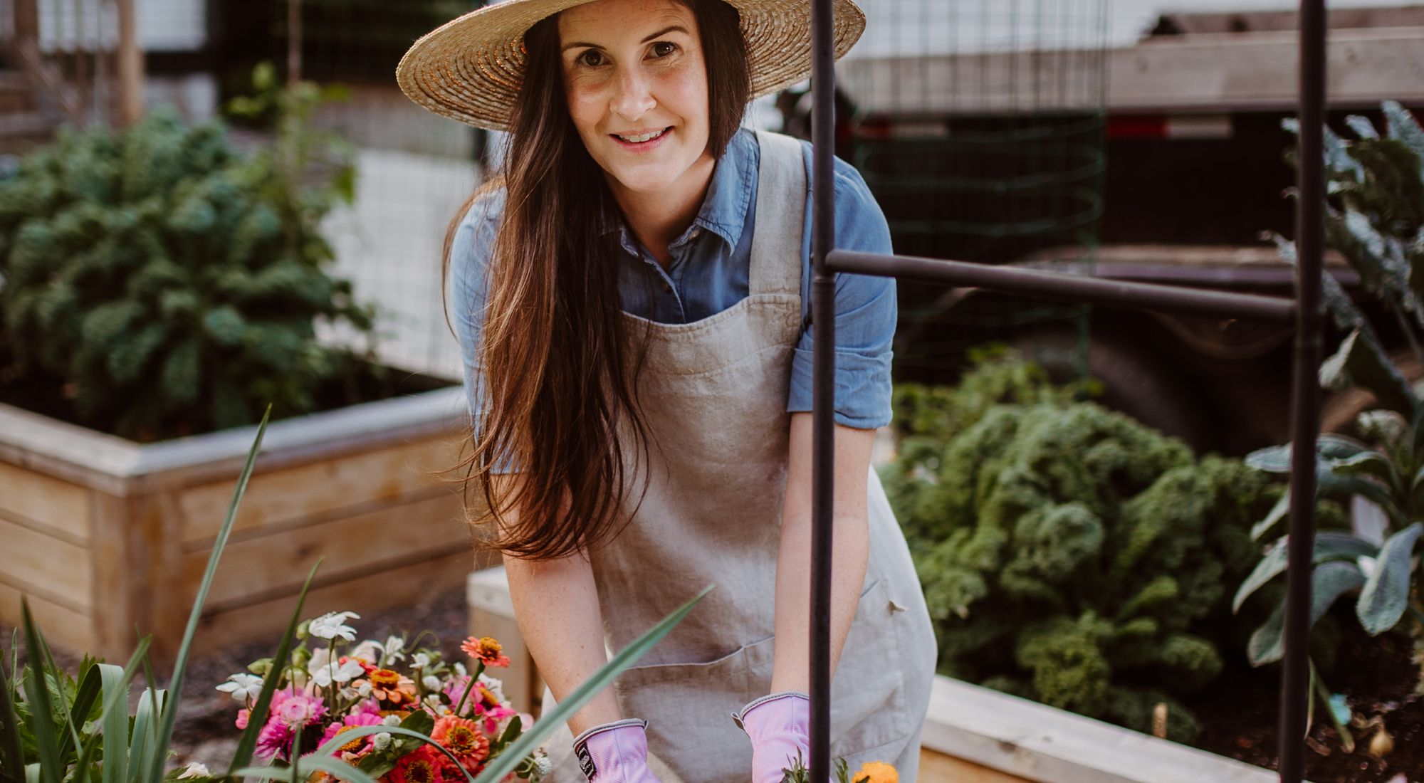 Personne en tablier de jardinage et gants en train de planter dans un jardin