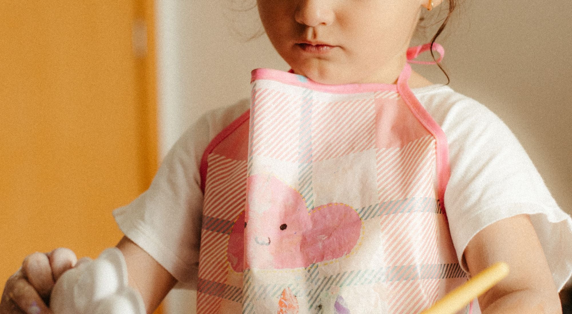 Enfant souriant portant un tablier coloré pour les activités scolaires