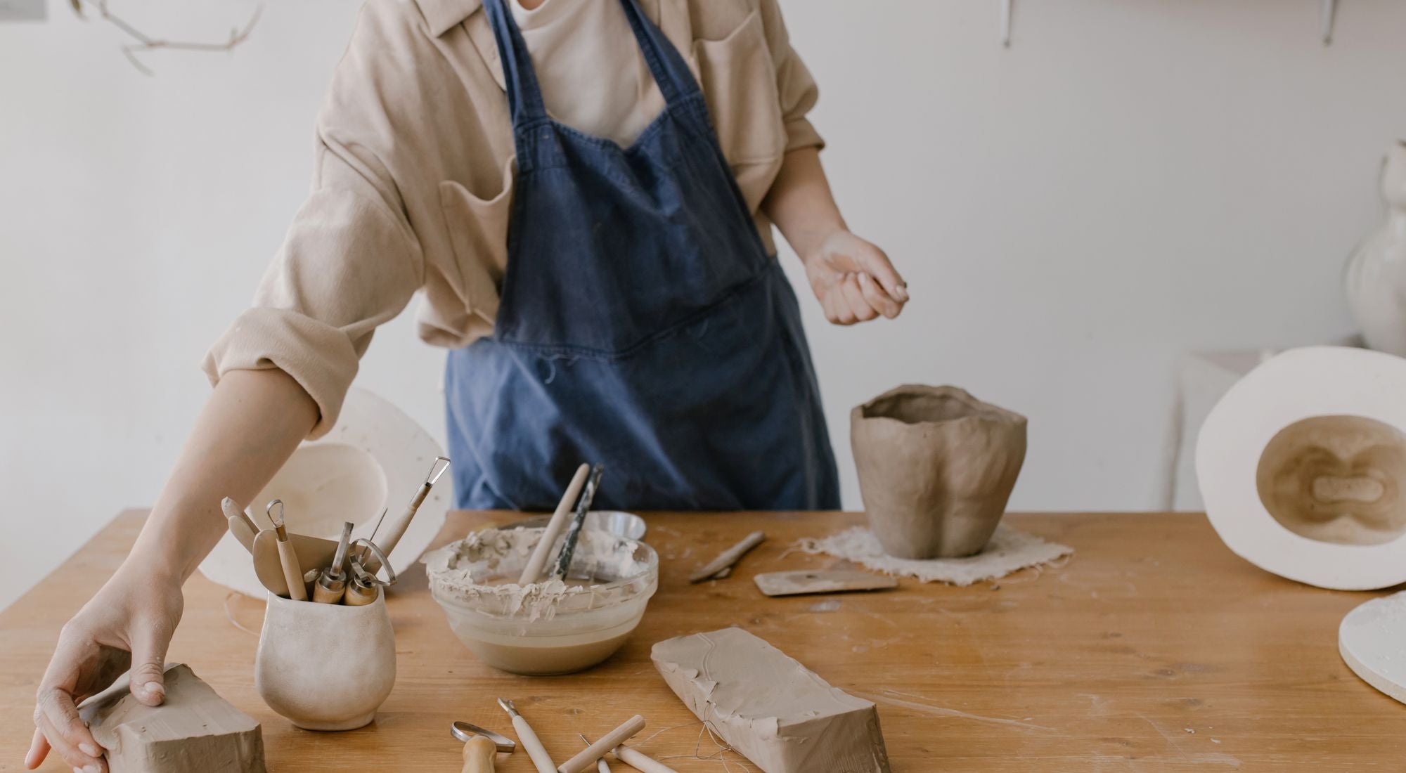 Céramiste en tablier de potier travaillant l'argile dans son atelier