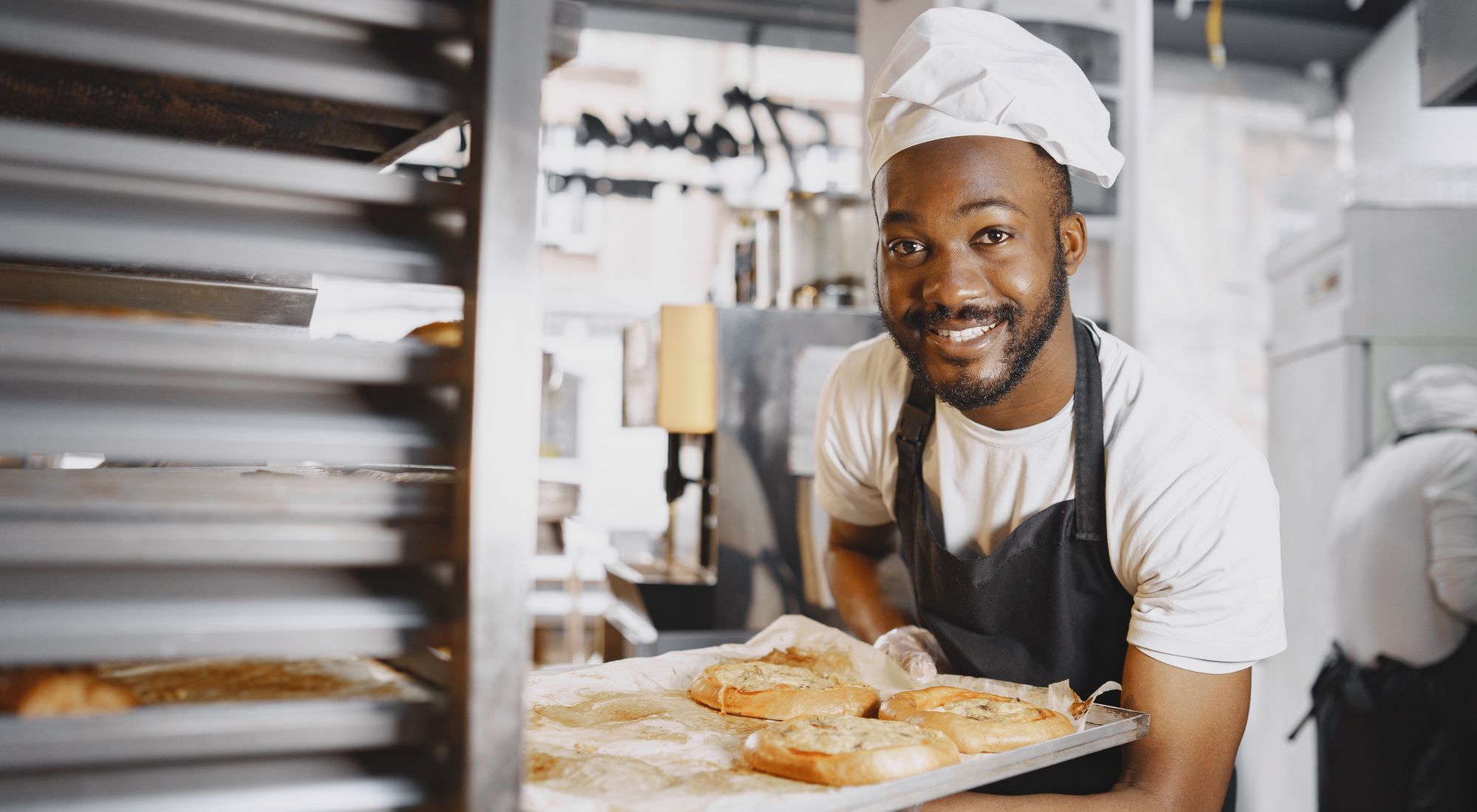 Artisan boulanger souriant en tablier propre devant son fournil, image de couverture