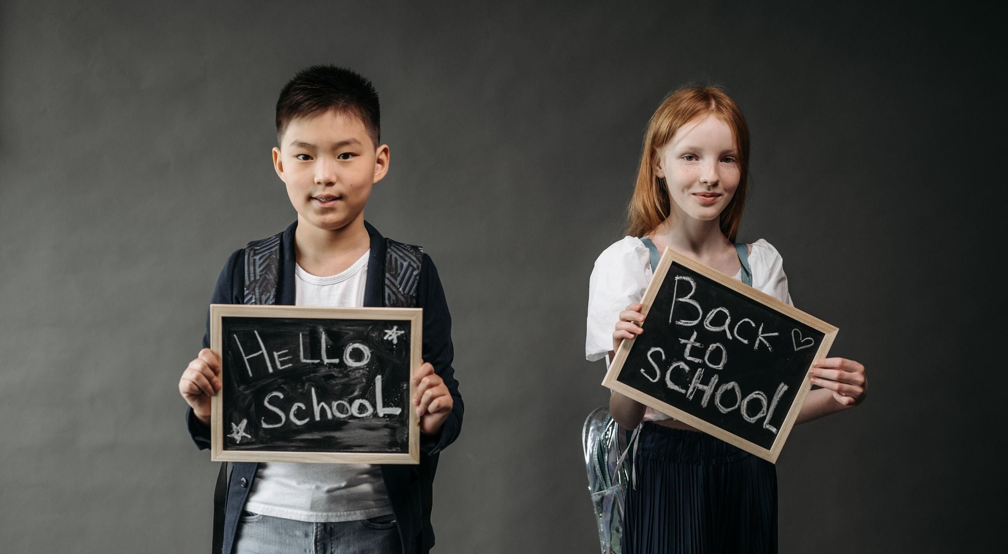 Enfants souriants avec tabliers et cartables, prêts pour la rentrée scolaire 2026