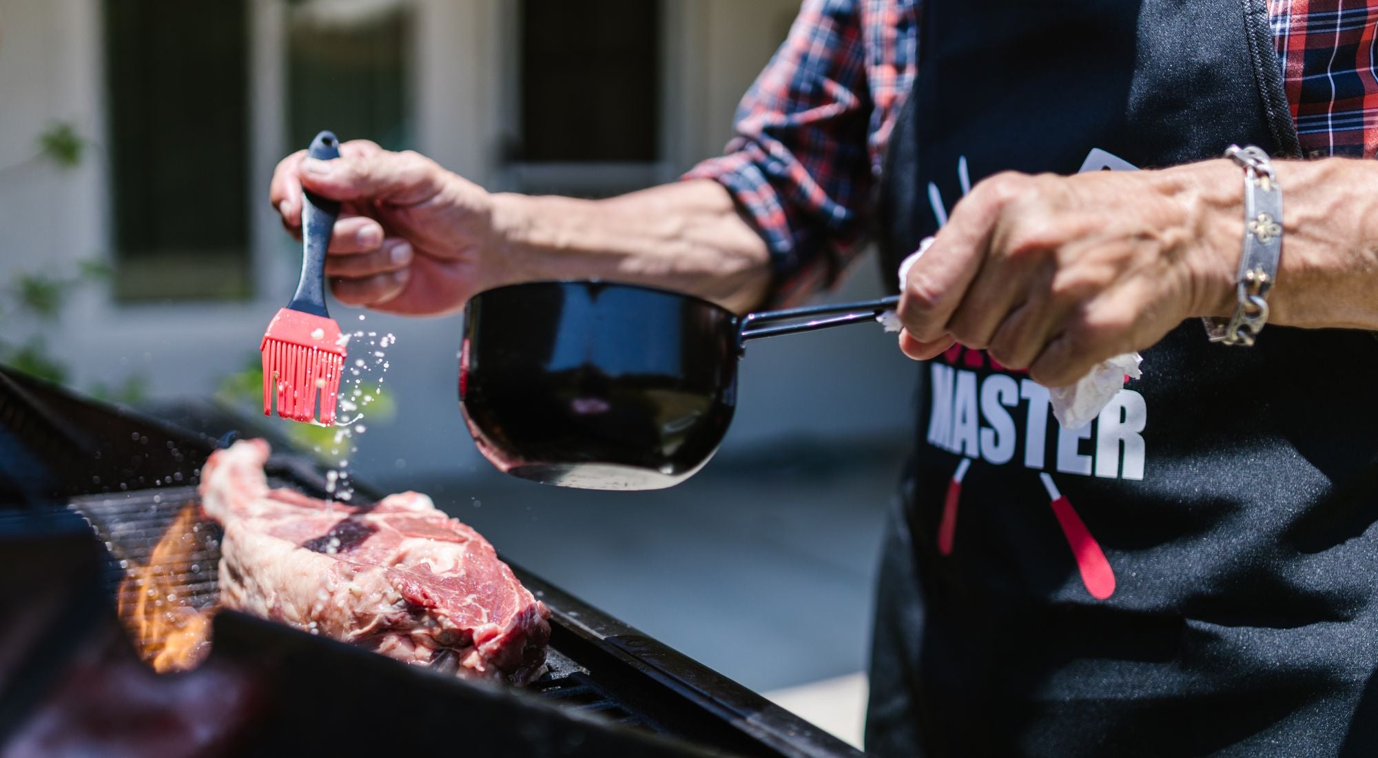 Maître du barbecue en tablier cuir devant un grill fumant en été
